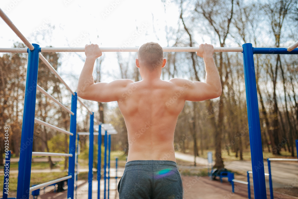 Outdoor Workout Guy Performs Intense Pull-Ups on a Bar. A fit male