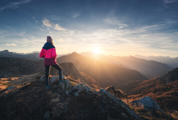 Wall Mural - young woman on mountain peak and beautiful mountain valley in haze at colorful sunset in autumn. dol