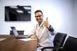 © littlewolf1989 - Caucasian doctor sitting in his office and holding thumbs up.