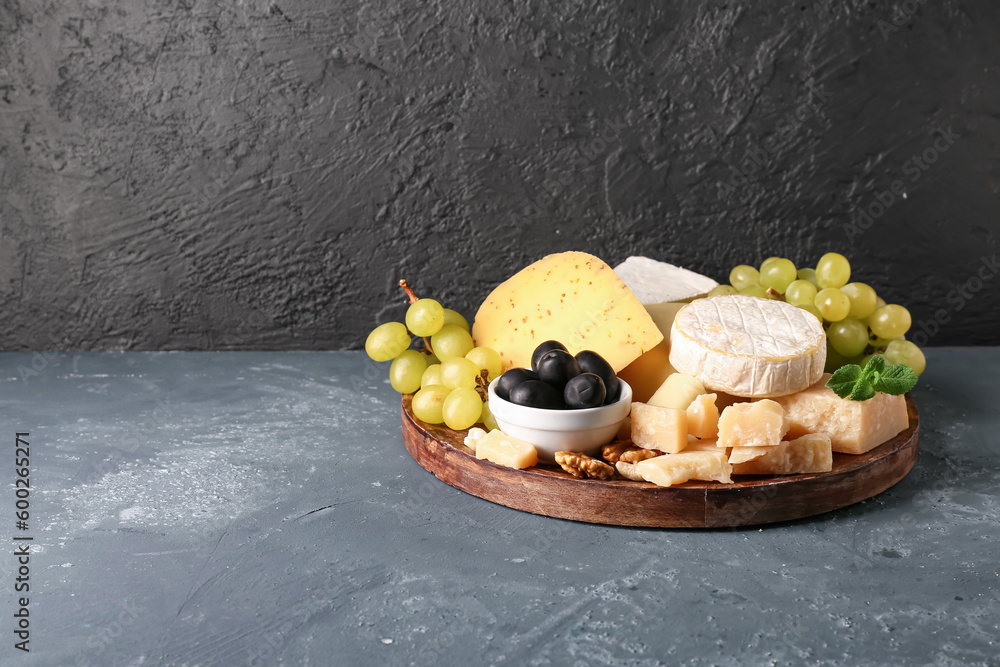 Plate with different types of tasty cheese and grapes on table