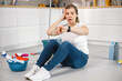 © prostooleh - Woman in red gloves sitting on a floor after doing cleaning in a kitchen