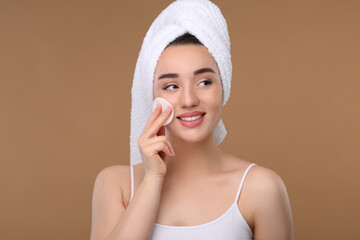 Wall Mural - Beautiful woman in terry towel removing makeup with cotton pad on beige background