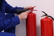 Man checking quality of fire extinguishers indoors, closeup