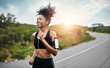 © Donson/peopleimages.com - Fitness, sports and happy woman running in a road with music for health, workout or cardio routine. Smile, exercise and African female runner in nature with podcast for training, motivation or energy