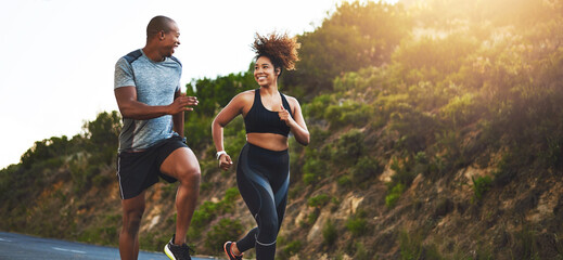Fitness, exercise and couple running in nature by a mountain training for a race, marathon or competition. Sports, health and athletes or runners doing an outdoor cardio workout together at sunset.