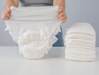 © Михаил Решетников - A woman chooses an adult diaper from a pile. Urinary incontinence problem.