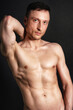 © vladorlov - Young attractive man with an athletic body on a black background.