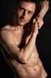 © vladorlov - Young attractive man with an athletic body on a black background.