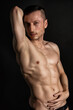 © vladorlov - Young attractive man with an athletic body on a black background.