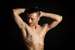 © vladorlov - Young attractive man with an athletic body on a black background.