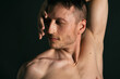 © vladorlov - Young attractive man with an athletic body on a black background.