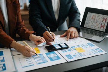  UX developer and ui designer brainstorming about mobile app interface wireframe design with customer breif and color code at office..