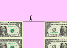 Silhouette Of Woman Walking Tightrope Between Two Blocks Made Of One Dollar Bills