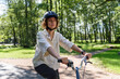 © molenira - Young woman in helmet riding on bicycle at park