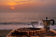 © maya1313 - Close-up white coffee cup and many coffee beans placed around on wood table with a beautiful seascape of nature background, concept coffee vacation travel, beautiful morning light background.