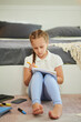 © DragonImages - Serious preteen girl sitting on floor and writing essay in textbook