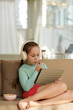 © DragonImages - Preteen girl eating snacks when watching her favorite show on tablet computer