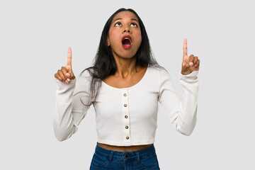 Wall Mural - Young Indian woman cut out isolated on white background pointing upside with opened mouth.