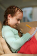 © DragonImages - Joyful girl sitting on couch at home and drawing in notepad