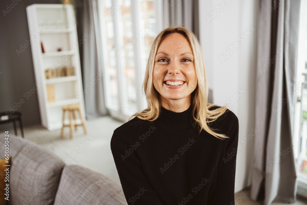 Laughing young blonde woman sitting on the sofa and looking at the ...