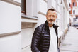 © contrastwerkstatt - Senior man standing on the sidewalk in the city and looking at the camera
