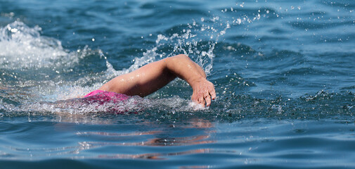 Wall Mural - Professional triathlete man swimming crawl in the ocean, freestyle crawl in ocean. Swimming man in clean ocean water. Open water swimming