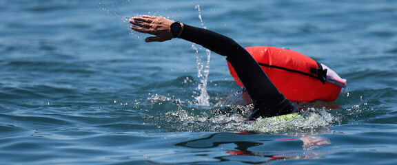 Wall Mural - Long distance swimming marathon swimmer in action. Swimming man in clean ocean water. Open water swimming