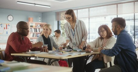 Fototapete - Grown Up Men and Women Working in Groups for an Assignment in Specialty Development Center. Adult Classmates Working on a Team Assignment, Young Female Teacher Explaining the Exercise Goals