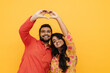 © Drobot Dean - Indian couple showing heart gesture with fingers isolated over yellow background