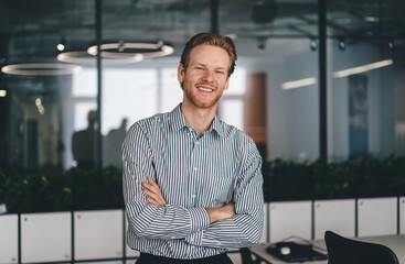 Cheerful male office worker standing with crossed arms