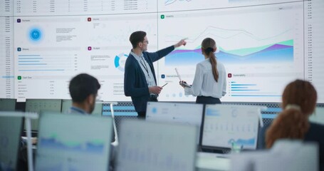 Aufkleber - Male Data Scientist And Female Project Manager Discussing Reports And Graphs On Big Digital Screen In Modern Monitoring Office. Diverse Employees Working Behind Computers in Deep Learning Company.