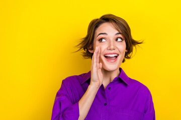 photo of nice cheerful person hand near mouth communicate look empty space isolated on yellow color 