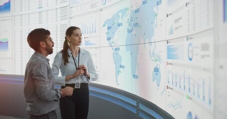 Aufkleber - Caucasian Female Manager Talks To Indian Male Distribution Expert In Front Of Big Digital Screen With Infographics And Map In Monitoring Office. Successful Man And Woman Working In Consulting Company.