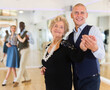 © caftor - Man and elderly woman performing ballroom dance in dancing room