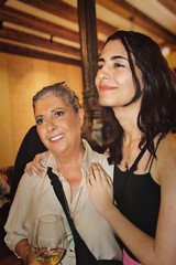 A mother and daughter hugging and smiling at a celebration.