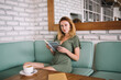 © BullRun - Smiling woman resting on sofa with book