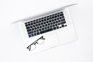 Laptop and glasses on a white background, top view.