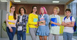© ihorvsn - Group portrait of smiling children with workbooks posing in row in modern school corridor. Six school age students in casual attire crossing arms and looking at camera.