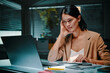 © DragonImages - Tired businesswoman working late, reading reports and documents in laptop