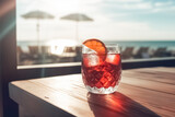 Fototapeta  - Refreshing Negroni Cocktail  with gin, campari martini rosso and orange, cold drink or beverage with ice on wood table in front of blue sky on summer sea. 