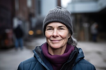 Canvas Print - Portrait of smiling middle aged woman in winter jacket and hat standing outdoors