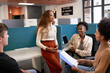© Meeko Media - Four diverse young colleagues huddle together, informal meeting open plan office