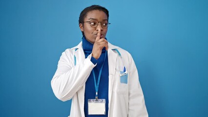 Canvas Print - African american woman doctor asking for silent over isolated blue background