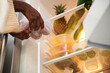 © DragonImages - Woman putting container with fresh fruits in refrigerator