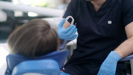 Wall Mural - Bite correction in modern dentistry clinic closeup of orthodontist showing female patient transparent aligners designed for teeth alignment woman at dental appointment