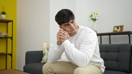 Poster - Young hispanic man stressed sitting on sofa at home