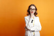 © Богдан Маліцький - pensive girl student in white suit and blazer thinks and dreams on orange background, young bussines woman