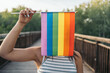 Unrecognizable young woman placing a rainbow flag vertically in front of her face. LGTBIQ+ Concept