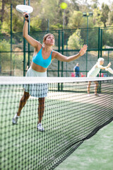 Wall Mural - Attractive woman padel tennis player training on court. Young woman using racket to hit ball.