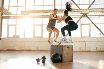 Wall Mural - athletic couple in sportswear at training in the fitness room, woman and man together at fitness training jump